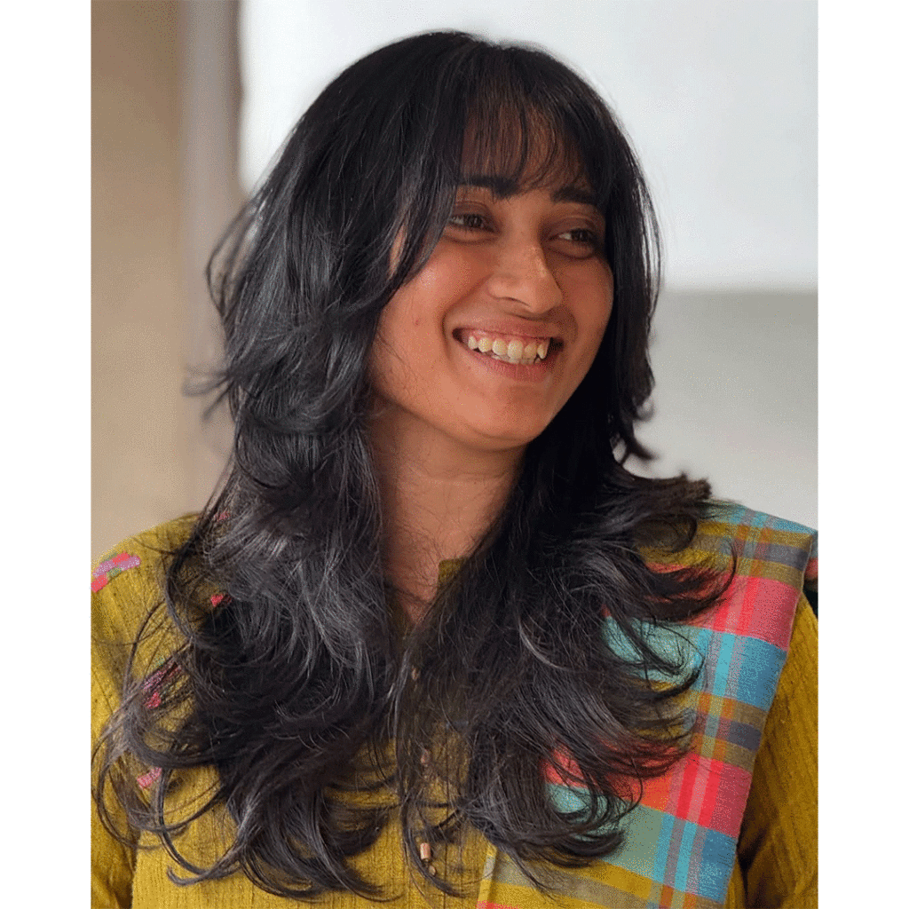 A soft layered wolf cut with flowing curtain bangs, giving volume and face-framing shape.