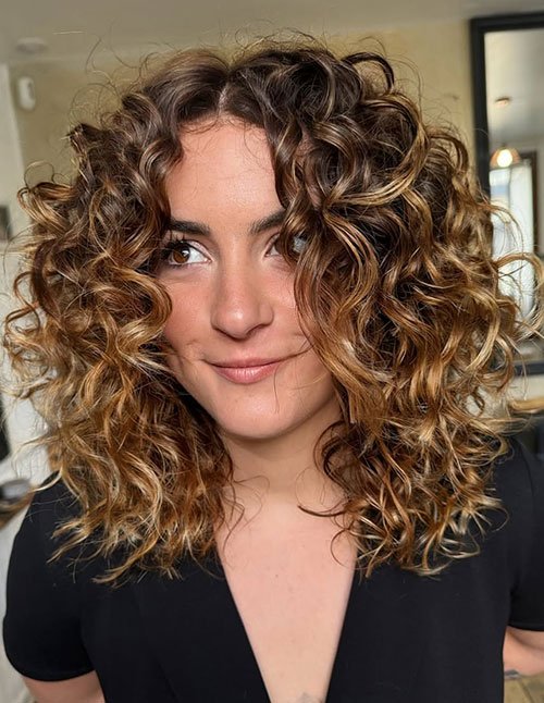 Medium length curly layered lob with caramel balayage