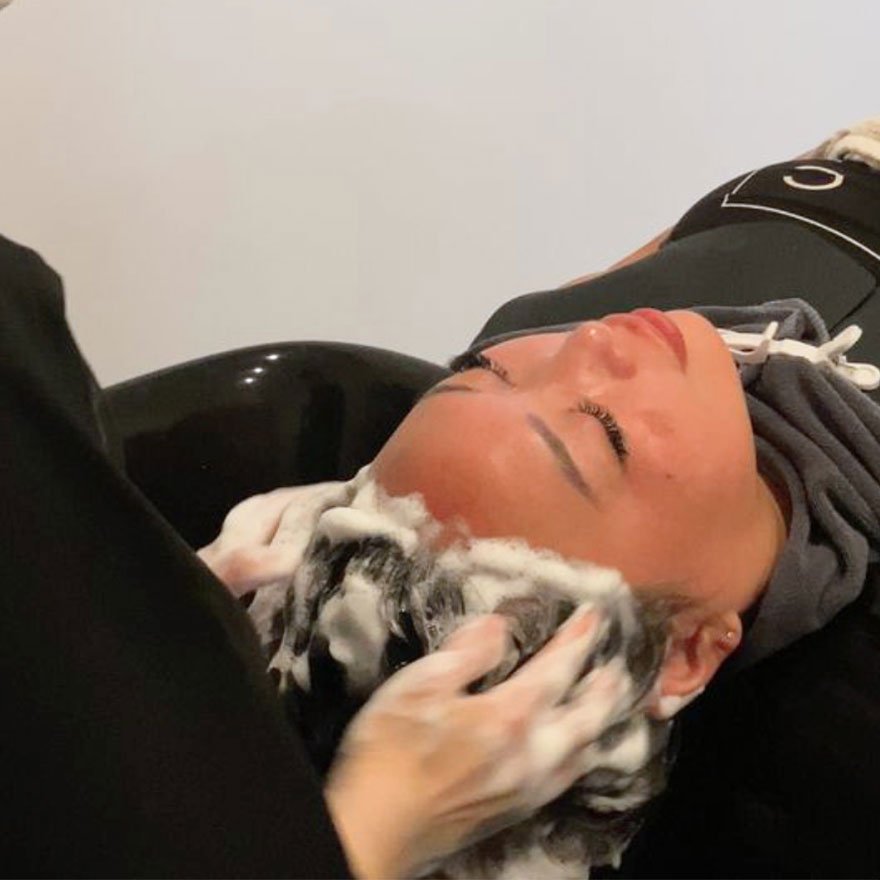 Woman getting her hair washed at a salon sink during a shampoo treatment