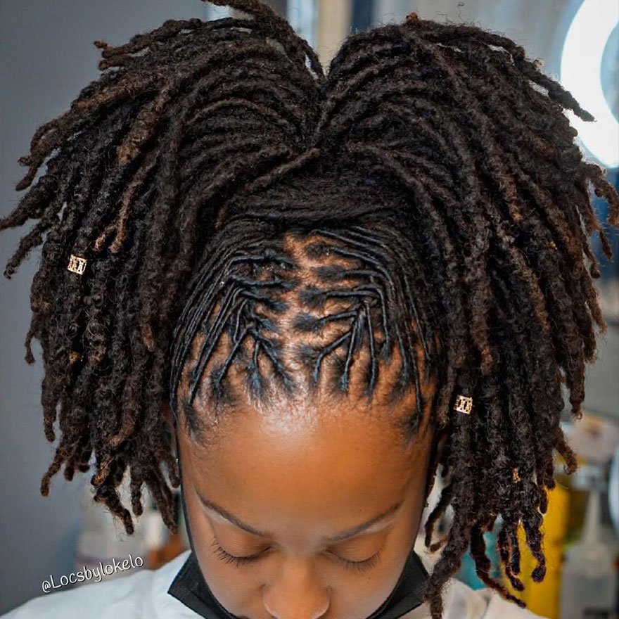 Close-up of a woman with neatly parted starter dreadlocks styled upward into a textured updo.