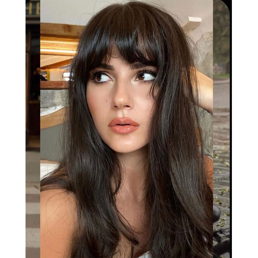 Long layered haircut with full curtain bangs on a woman.