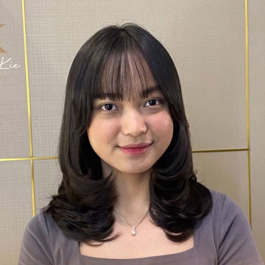 Korean layered haircut with see-through bangs framing the face.