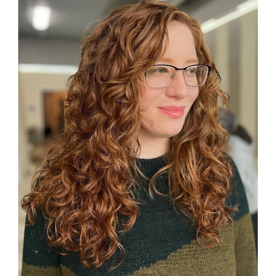 Long layered cut for naturally curly hair with soft volume and defined curls.