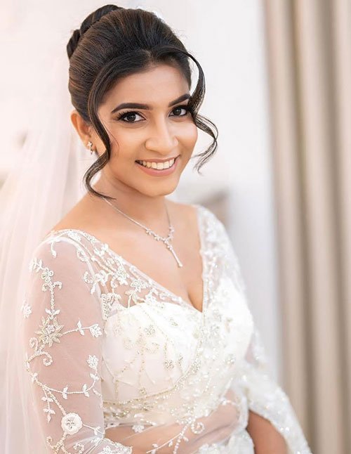 Soft textured bridal updo with loose curly tendrils framing the face