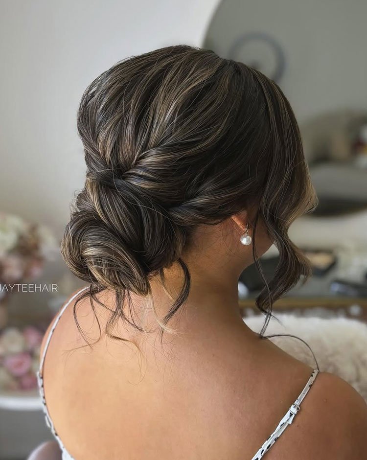 Low textured low bun with soft face-framing waves, viewed from the back.