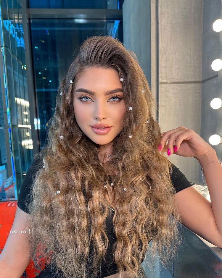 Soft boho crimped waves hairstyle with beads on brunette woman.