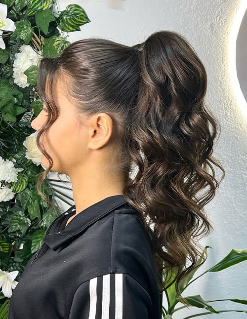 Curly high ponytail with face-framing tendrils