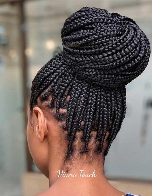 Back view of a woman’s head with small-to-medium braids pulled into a large, round high bun.