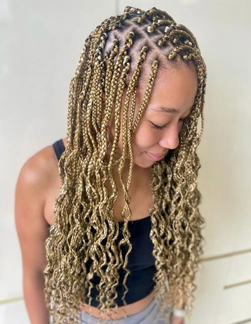 Bohemian box braids with blonde highlights, featuring loose, wavy curls at the ends for a relaxed finish.