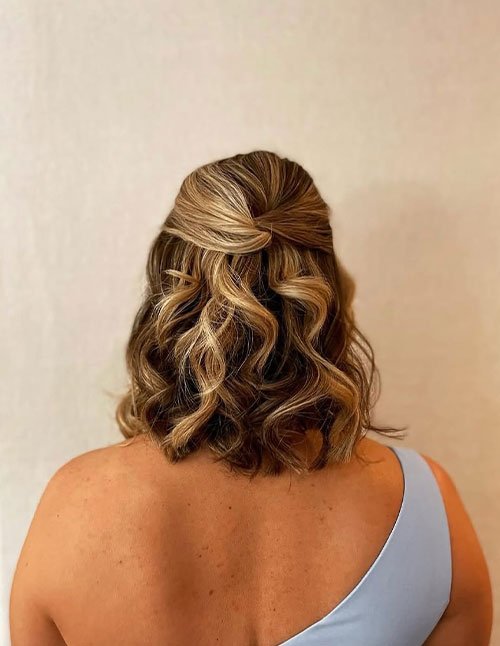 Boho half-up hairstyle on short wavy hair with loose curls.