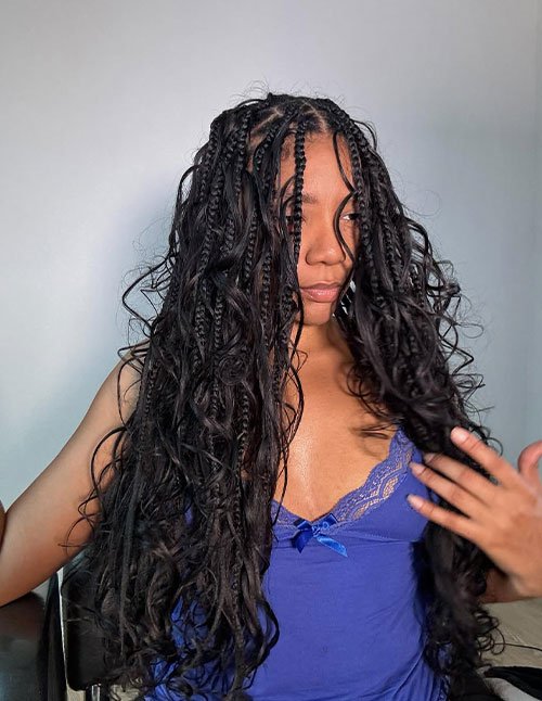 Boho-style braids mixed with loose, flowing curls, creating a soft, natural look with textured volume and face-framing strands.