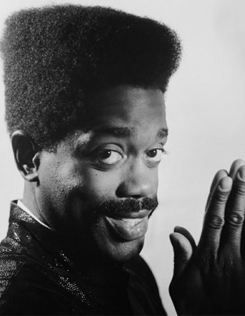 Black-and-white portrait of a man wearing a boxy 90s flat top haircut, with a high, squared shape and clean, sharp edges.