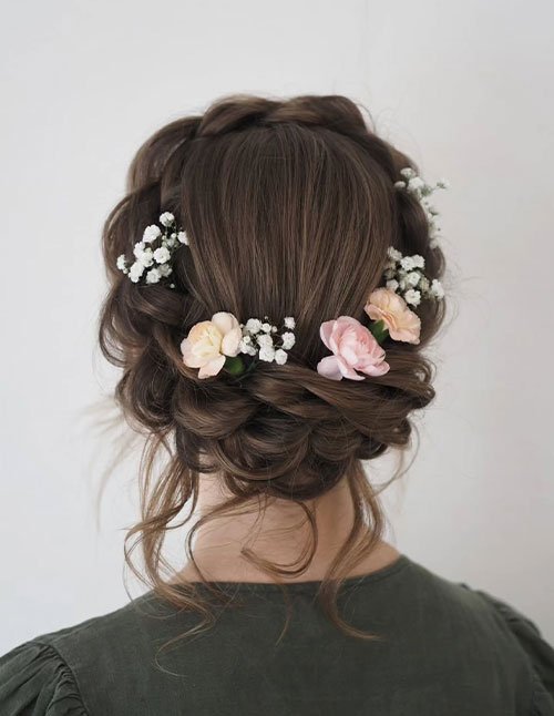 Braided crown hairstyle with soft updo and floral accents