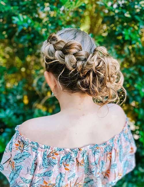 Boho braided formal updo with soft curls gathered into a low bun, viewed from the back.