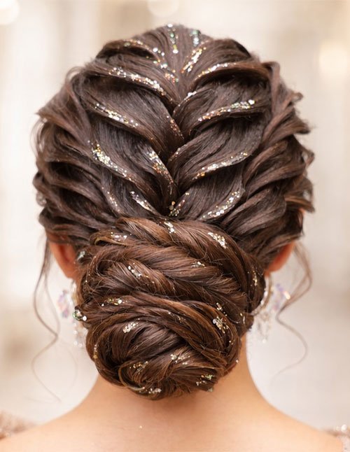 Back view of a braided formal low bun featuring an elegant French braid flowing into a smooth, textured bun with subtle sparkle accents.