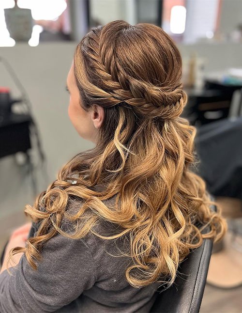 Braided half-up hairstyle with a side braid wrapped across the back, blending into loose, curled hair.