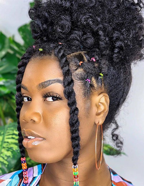Braided puff updo with a high curly puff, side braids, and beaded face-framing twists.