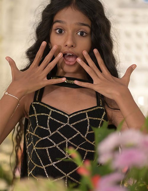Front view of a girl with long dark hair styled in brushed-out waves, featuring soft, loose texture and a center part.
