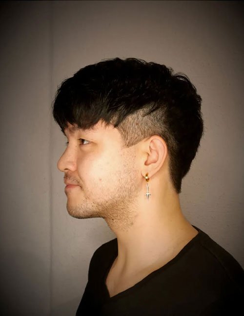 Man wearing a Caesar undercut haircut with a short textured fringe and shaved sides.