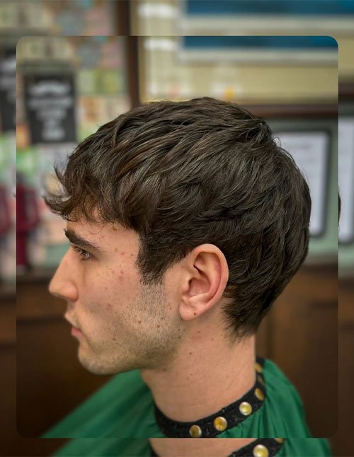 Side profile of a man with a classic Caesar haircut, featuring short, evenly cut hair with a subtle forward fringe and clean, natural sides.