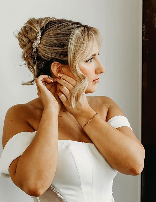 Classic French twist updo with soft side bangs and a decorative hair pin.