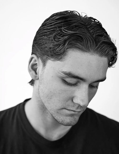 Man wearing a classic slicked-back hairstyle with neatly combed hair swept straight back and a smooth, polished finish.