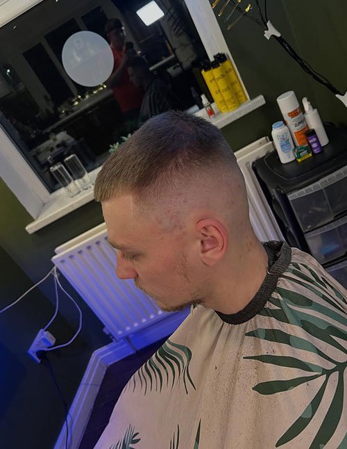 Clean buzz fade haircut with a short buzzed top and a smooth fade on the sides for a sharp finish.