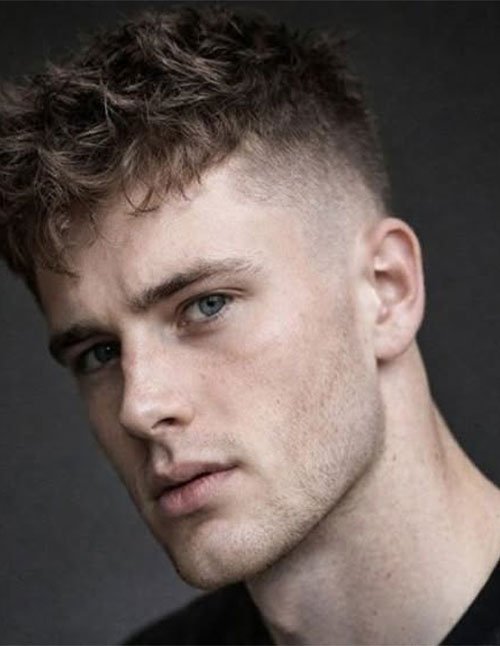Close-up of a man with a textured crew cut and a low fade on the sides, featuring a soft, clean blend around the temples.