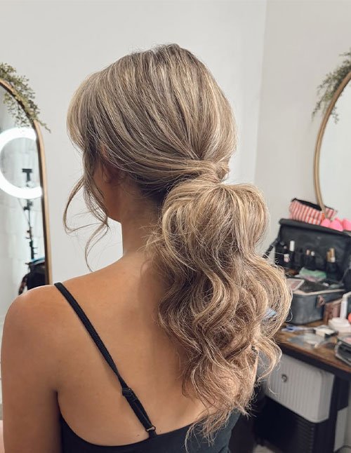 Half-up ponytail with soft waves and loose face-framing pieces, viewed from the back.