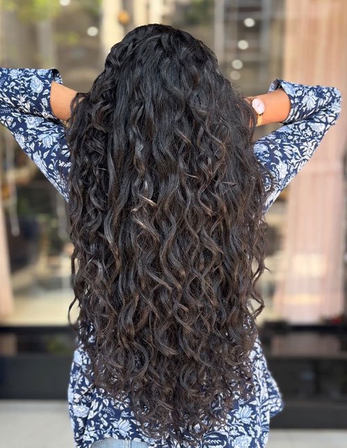 Back view of long hair with defined layered curls and natural shine.