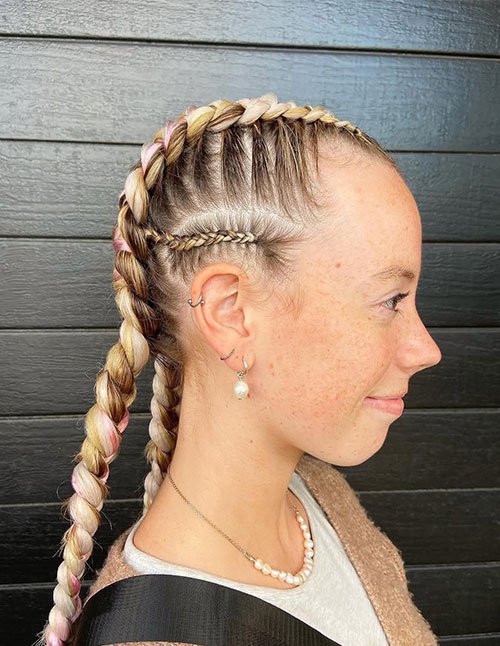 Side-profile showing double Dutch braids with soft pink highlights, neatly braided close to the scalp and finished into long plaits.