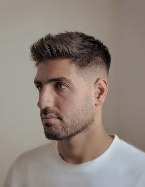 Drop fade quiff haircut with a curved drop fade on the sides and a textured quiff on top styled upward.