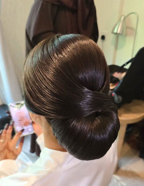 Sleek low bun updo on thick hair with a smooth twisted wrap, viewed from above.
