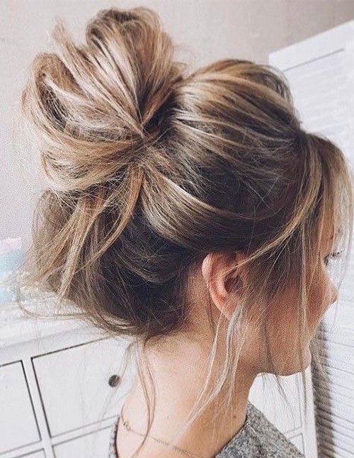Effortless messy top knot with loose strands and soft volume.