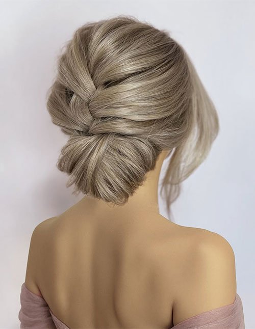 Elegant braided updo with a smooth side braid woven into a low chignon, back view.