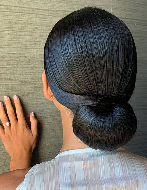 Sleek elegant low chignon bun on straight black hair.