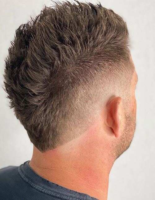 Faux hawk fade with a textured, spiky top and a clean mid-to-high fade tapering down the sides and back.