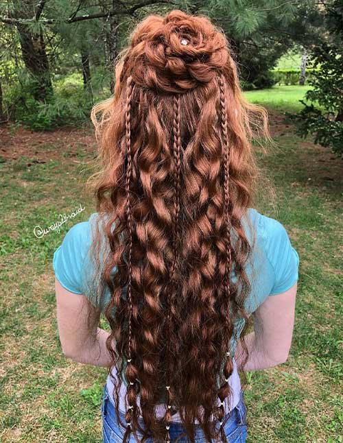 Floral braided half-updo with a rose-like braid bun and long wavy red hair.