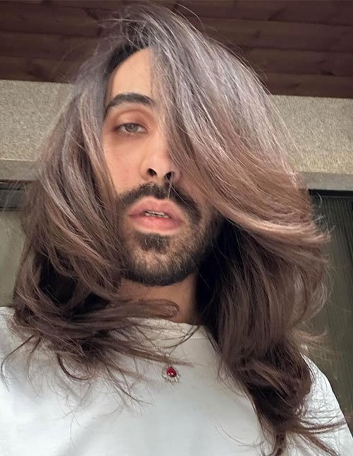 Man with long layered flow hairstyle featuring shoulder-length hair and soft face-framing layers.