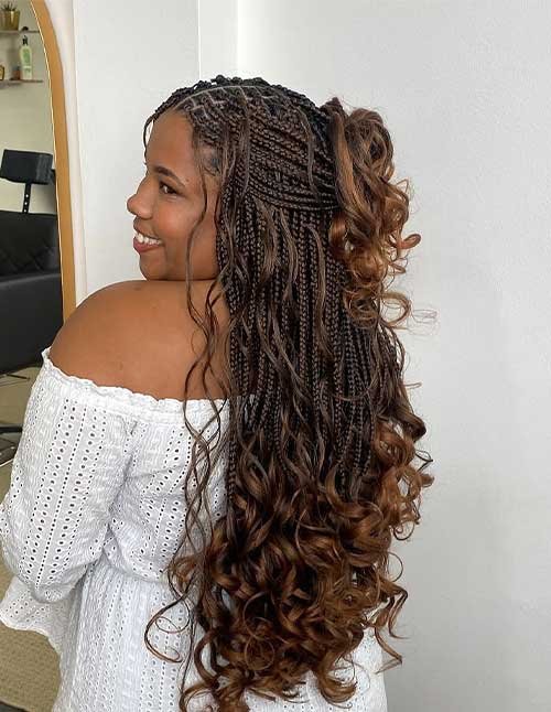 French curl braids style with small box braids and long bouncy curls, featuring a half-up ponytail and warm brown tone.