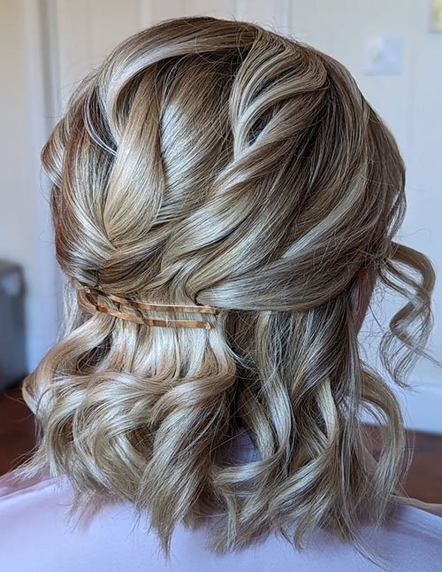 Glam half-up half-down bridal hairstyle on short blonde hair with a barrette.