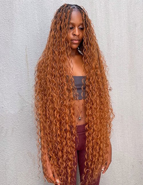 Goddess braids with a neat center part flowing into long, loose waves in a warm copper tone.