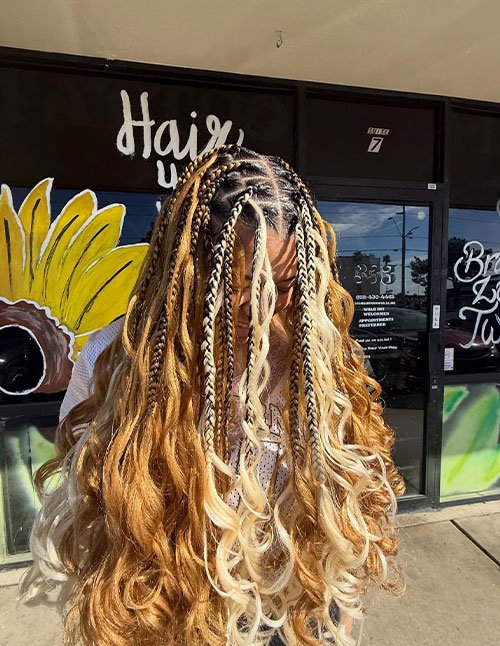 Golden braids with curls featuring mixed-size braids and loose wavy curls, with blonde face-framing pieces and a warm honey-gold blend.