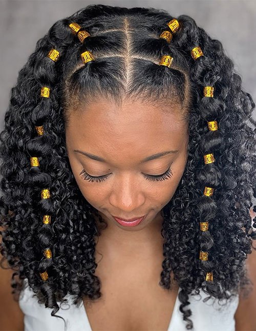 Golden curly braided hairdo with a center part, featuring chunky braided sections and defined curls decorated with gold hair cuffs.