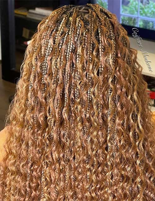 Golden knotless goddess braids with curly lengths flowing down the back, featuring soft blonde highlights and a natural braided pattern.