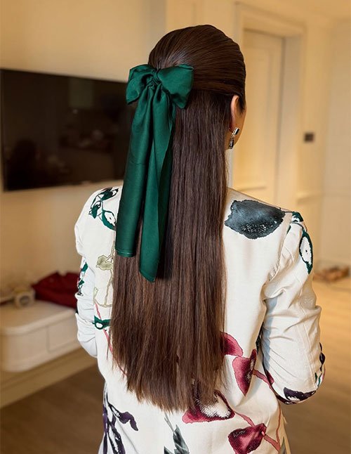 Green ribbon hairstyle with a large bow tied at the back, holding a sleek half-up section over long straight hair.