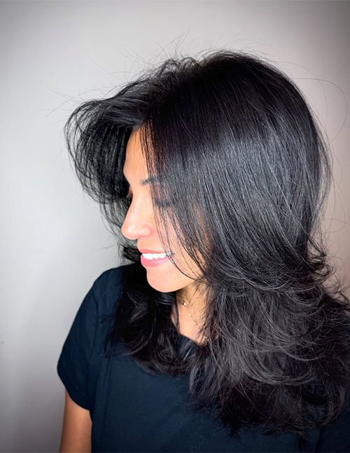 Woman with medium-length layered hair styled with natural texture and soft volume.