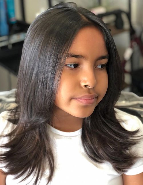 Girl with medium-length layered hair styled straight with a sleek, smooth finish.