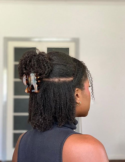 Simple half-up hairstyle for short natural hair secured with a claw clip.