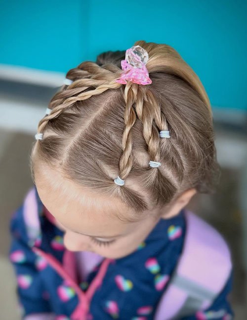 Top view of a young girl with hair styled in a half-up ponytail using multiple small rope twists secured with elastics and a decorative clip.